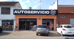 Fachada naranja del Autoservicio Teo con autos estacionados