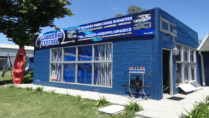 Local de Guardería Central: edificio azul con cartel "Accesorios para casas rodantes" y teléfonos de contacto
