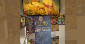 Cartel y pósters del personaje Curly en la vidriera de la heladería, con el texto "Auténtico helado artesanal"