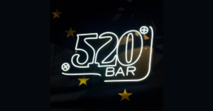 Cartel de neón con el texto "520 Bar" y estrellas sobre fondo negro