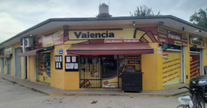Fachada amarilla del Maxikiosco y Polirubro Valencia con toldo rojo